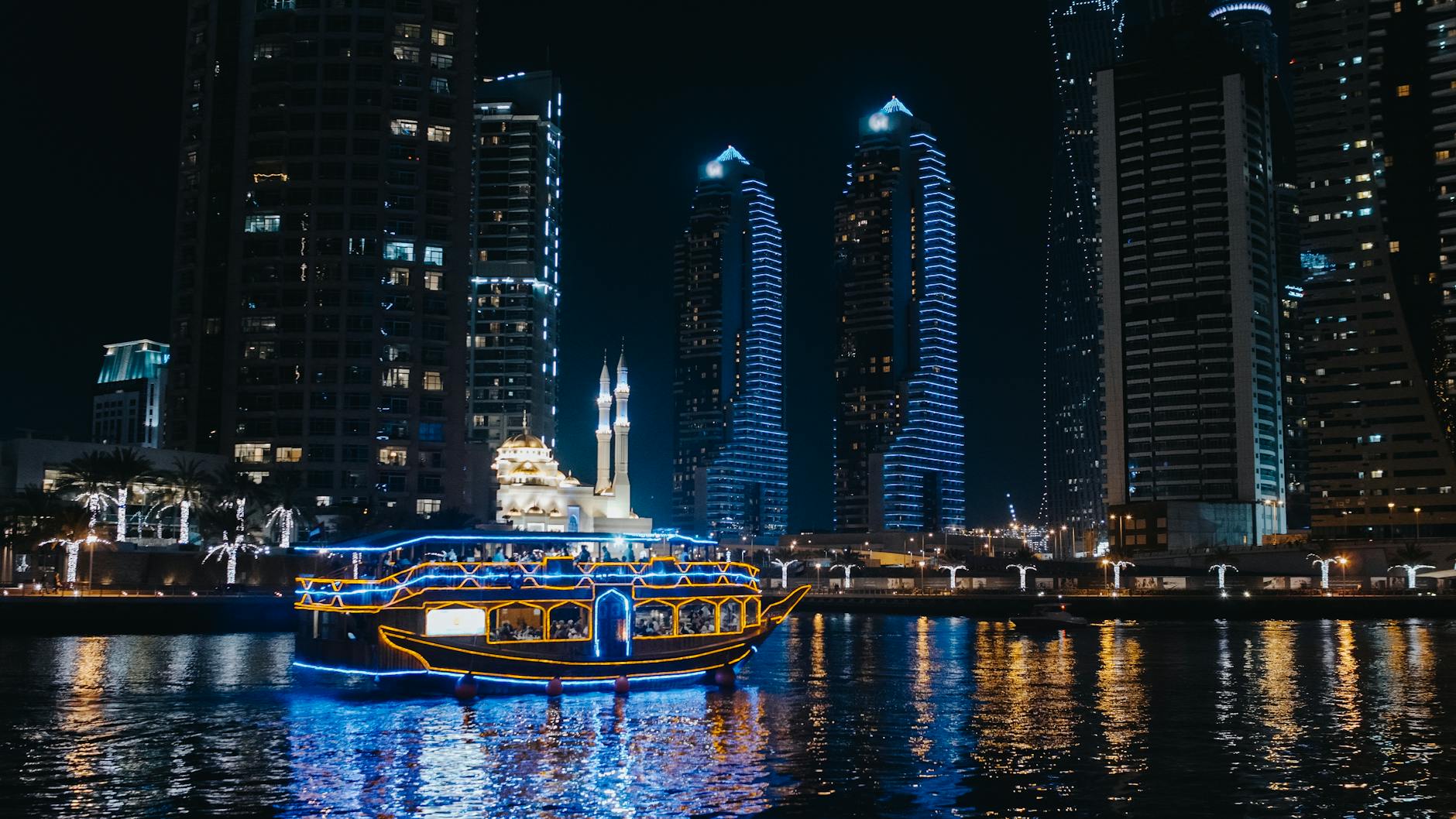 a boat sailing on river near city buildings during night